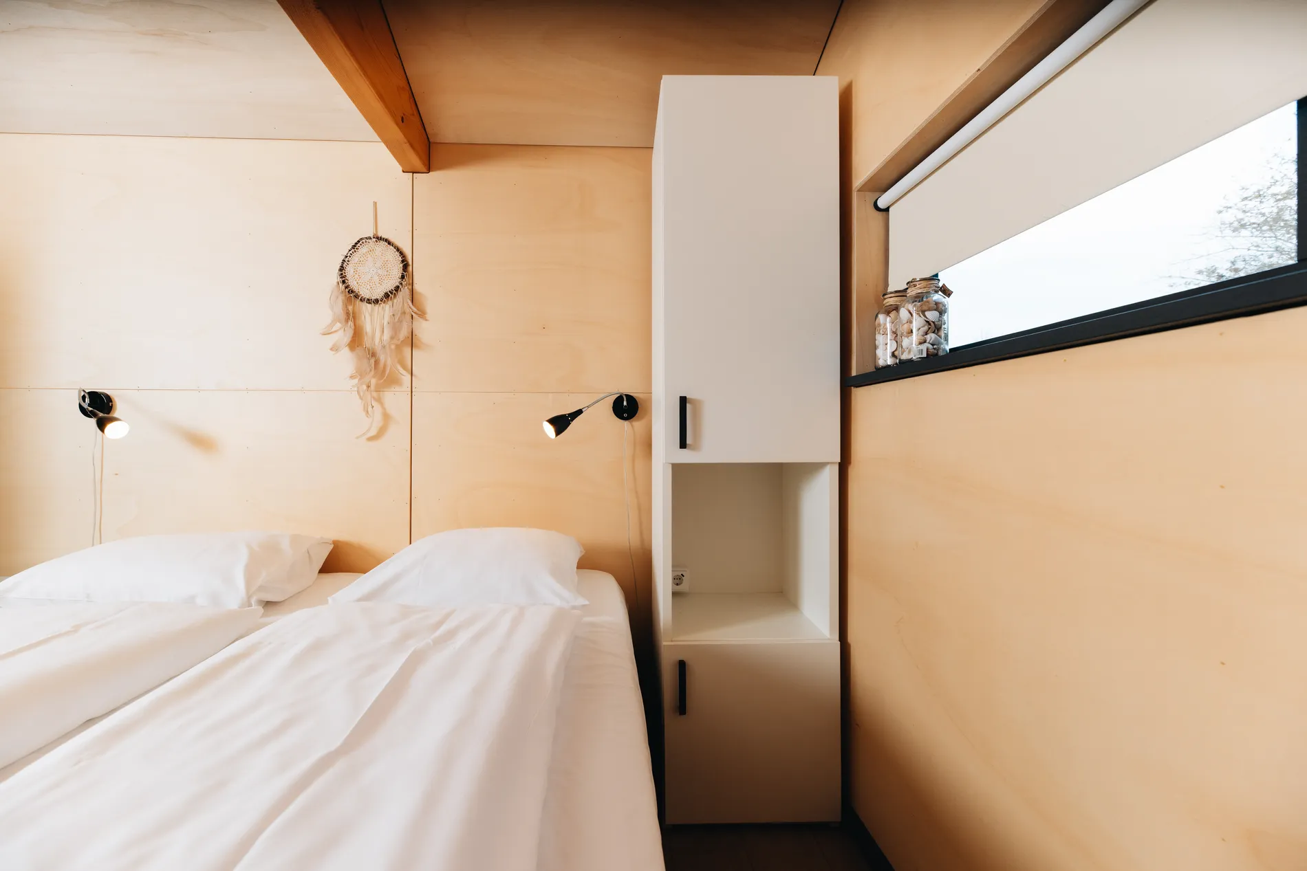 Sfeervolle slaapkamer met houten interieur en praktische witte inbouwkast.